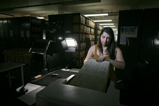 Rhyl Journal: Photo via PA shows Findmypast technician Laura Gowing scans individual pages of the 30,000 volumes of the 1921 Census at the Office for National Statistics (ONS) near Southampton.