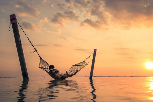 Rhyl Journal: A man relaxing over the water in a hammock. Credit: Canva