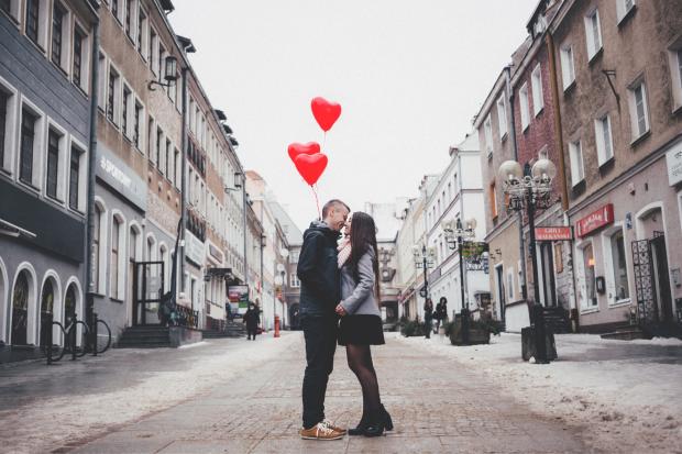Rhyl Journal: A couple embracing on the street in front of heart balloons. Credit: Canva