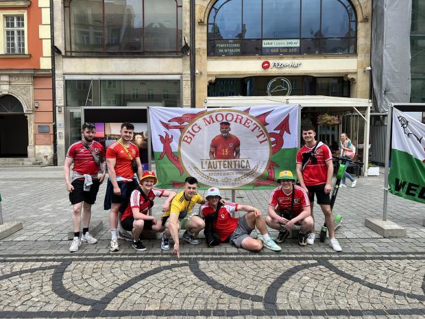 Rhyl Journal: Wales superfan Cai Jones and friends with their popular 'Big Mooretti' flag. Photo: Cai Jones