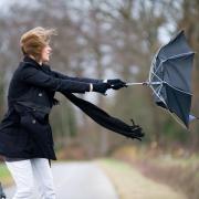A young woman is fighting against the storm with her umbrella.